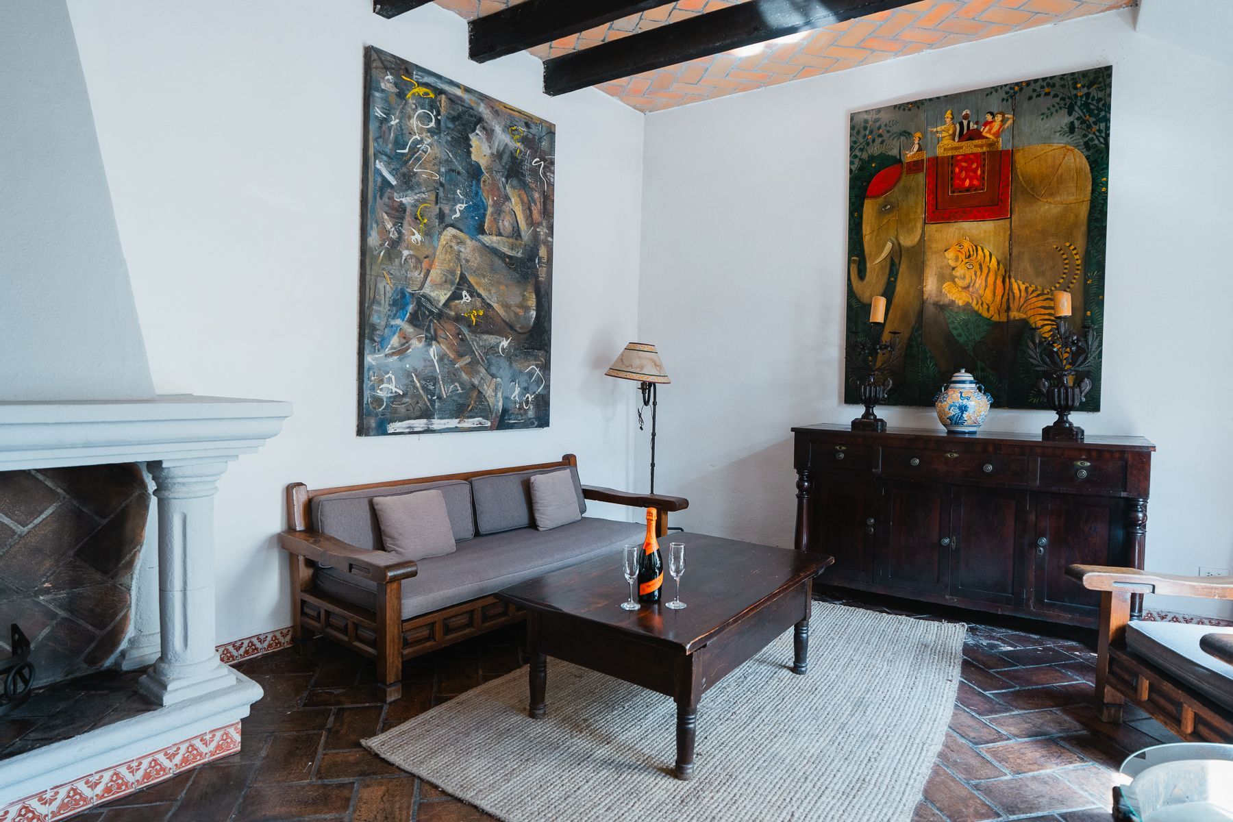 Sala de estar con muebles de madera oscura, obras de arte de gran tamaño y chimenea.