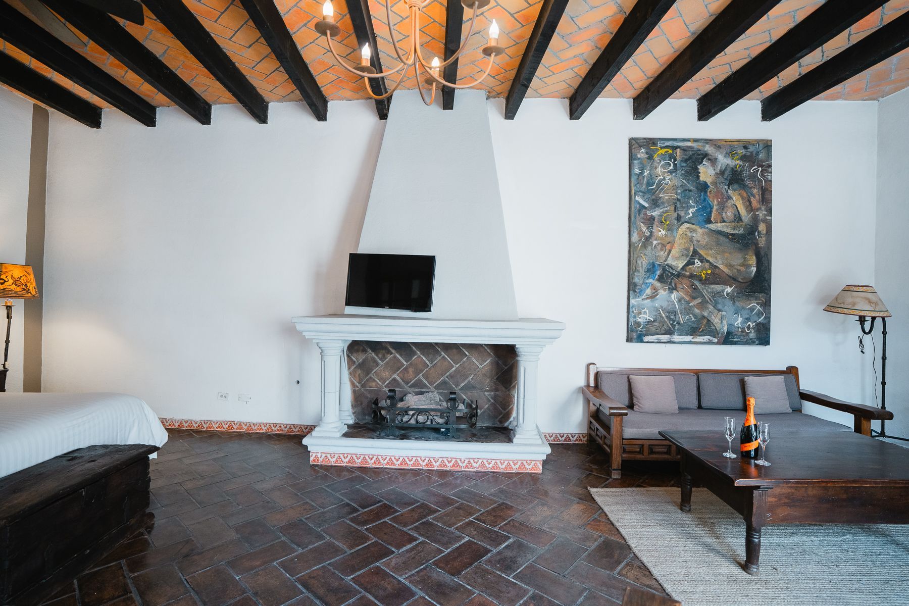 Sala de estar con chimenea, sofá, arte y vigas a la vista.