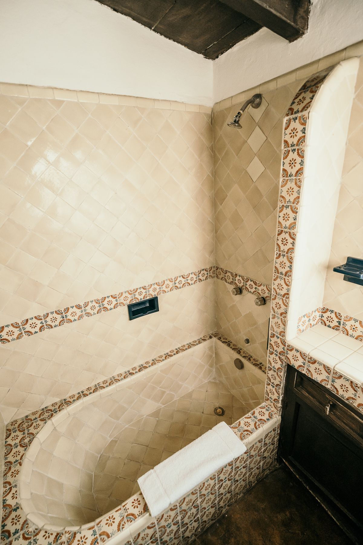 Baño con bañera y paredes alicatadas. Combinación de colores marrón y crema.