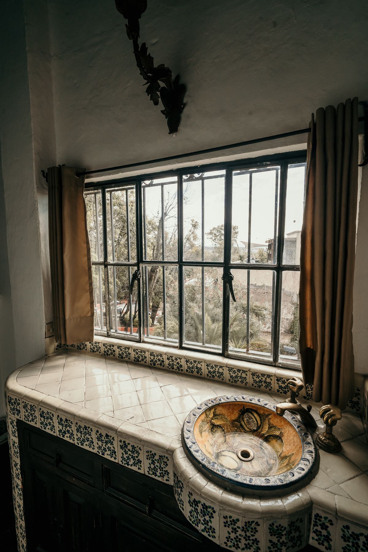 Baño con lavabo, ventana y encimera de azulejos decorativos.
