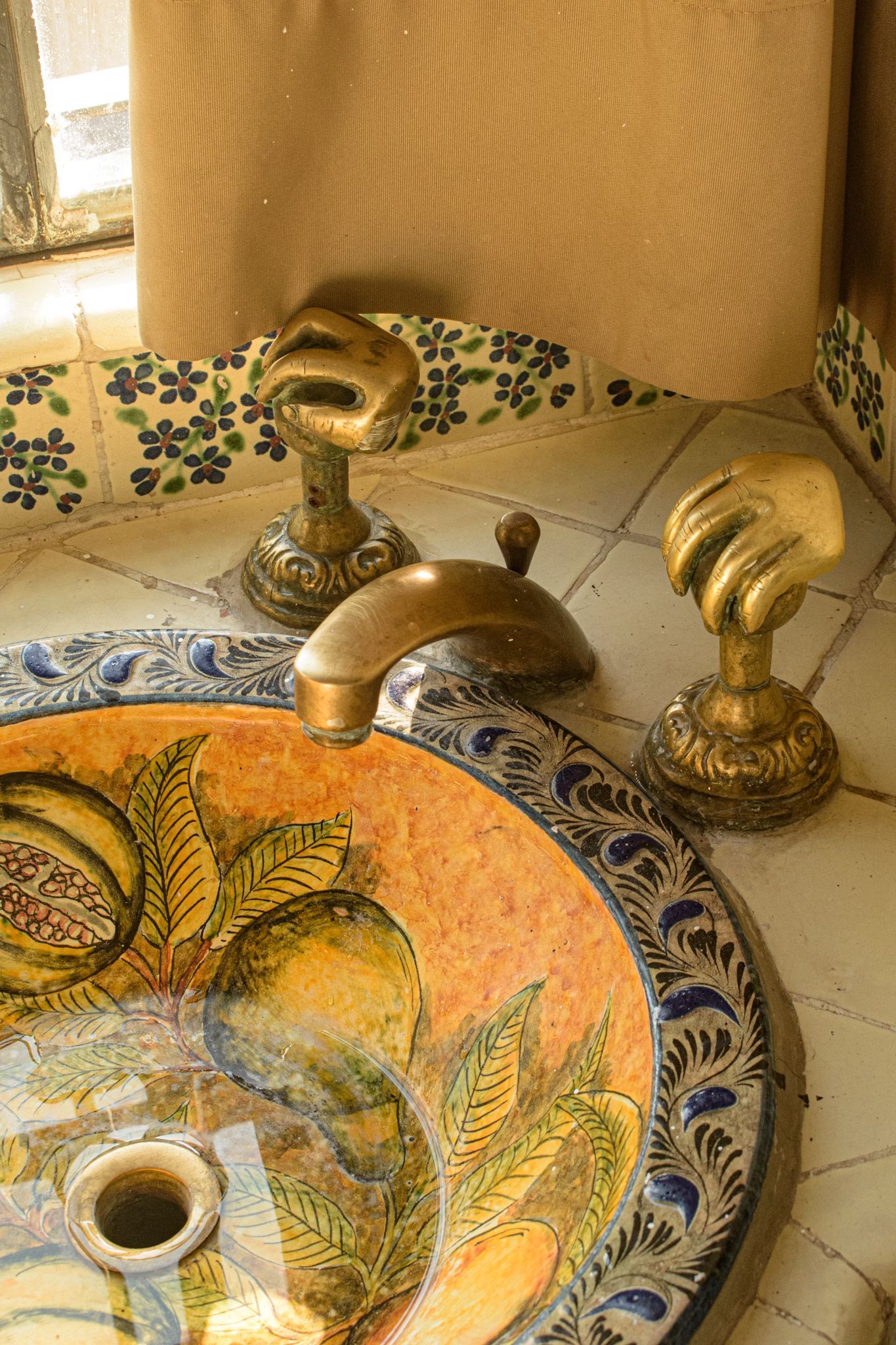 Primer plano de un lavabo decorativo con grifos dorados hechos a mano y un lavabo pintado.