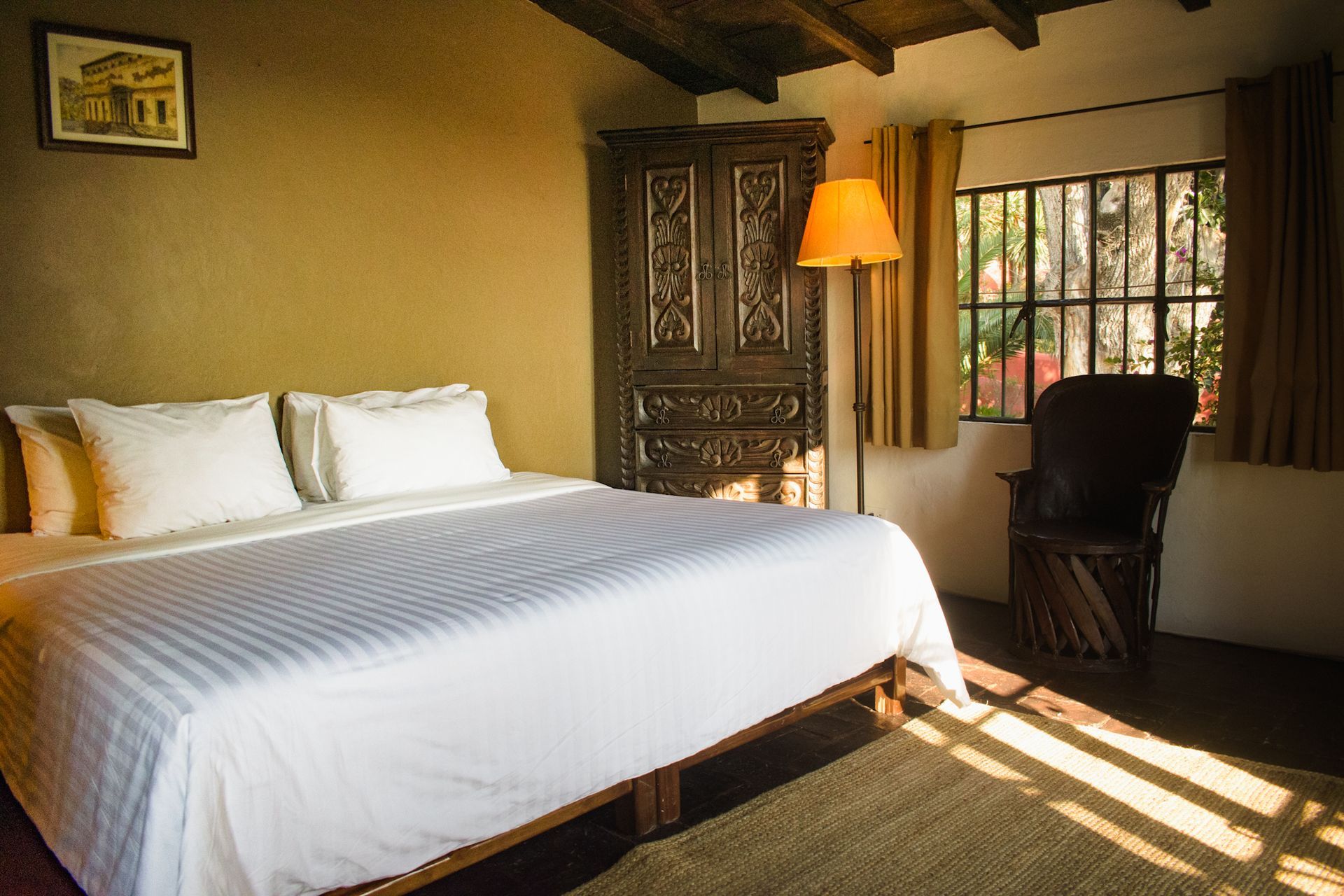 Dormitorio con cama grande, muebles de madera y ventana con luz natural.