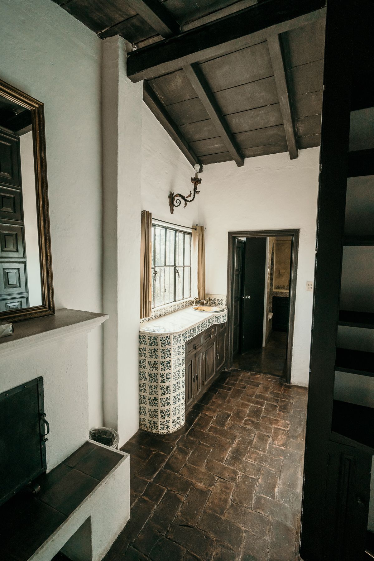 Pasillo con vigas de madera oscura en el techo, azulejos estampados, armarios empotrados y una puerta.