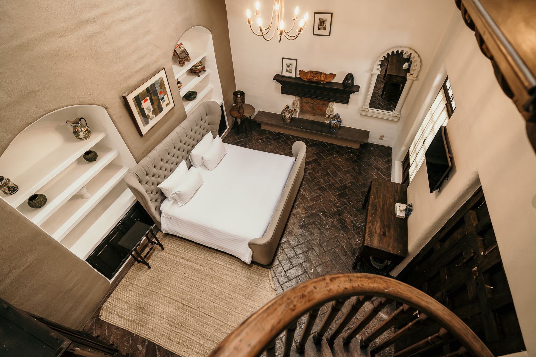 Vista aérea del dormitorio con cama, chimenea, estantes y piso de madera.