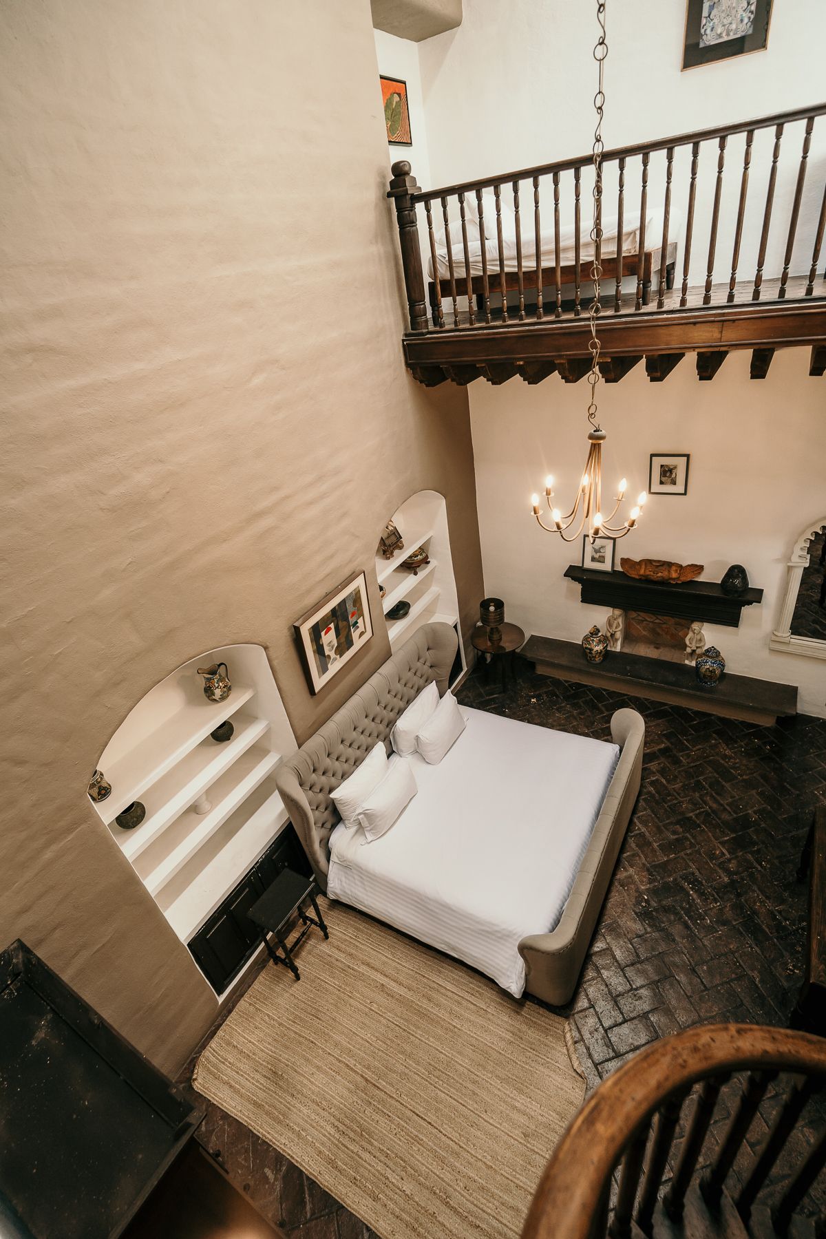 Dormitorio con altillo, techos altos, cama grande, chimenea, estanterías y balcón.