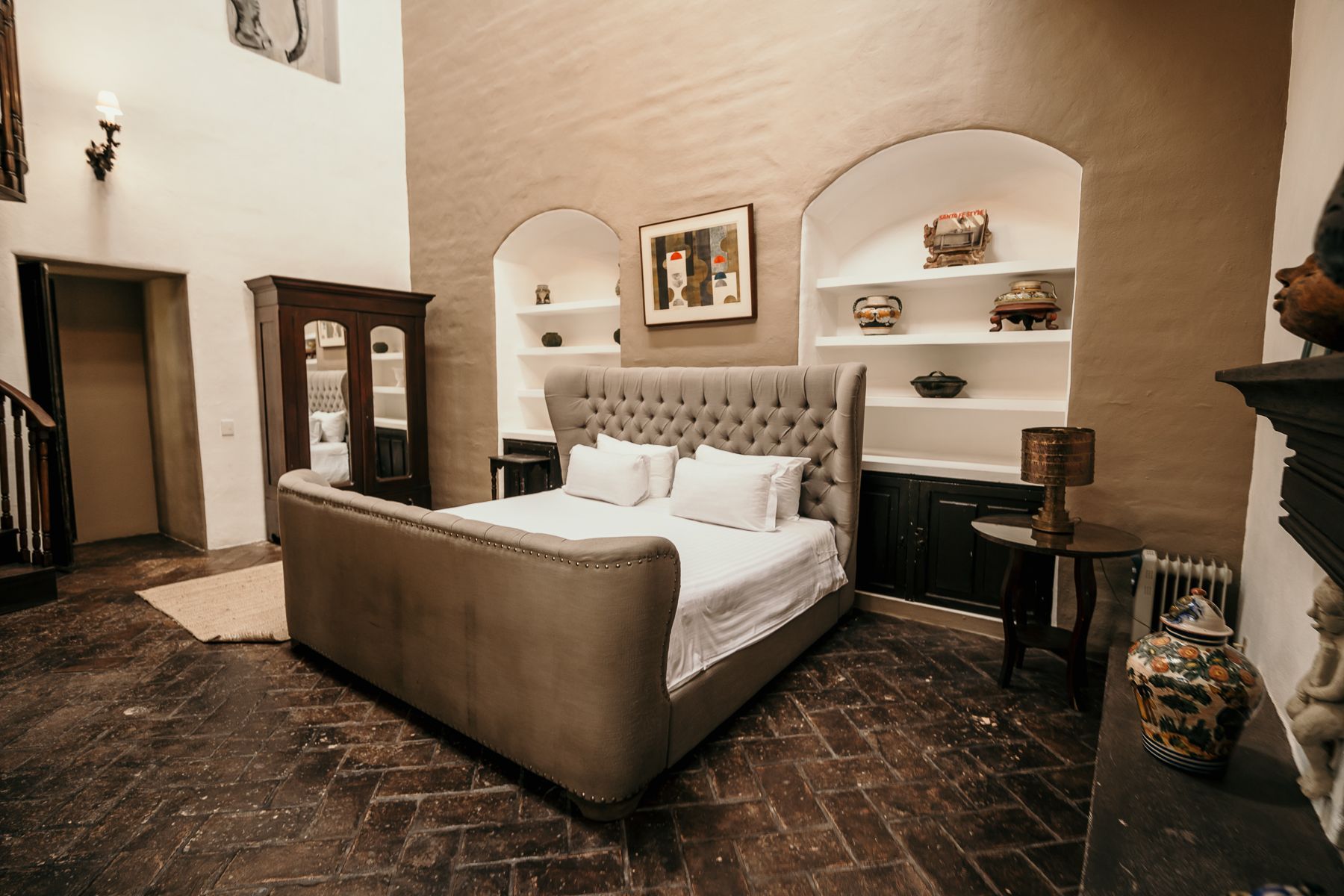 Amplio dormitorio con cama grande, estantes empotrados y piso de madera oscura.