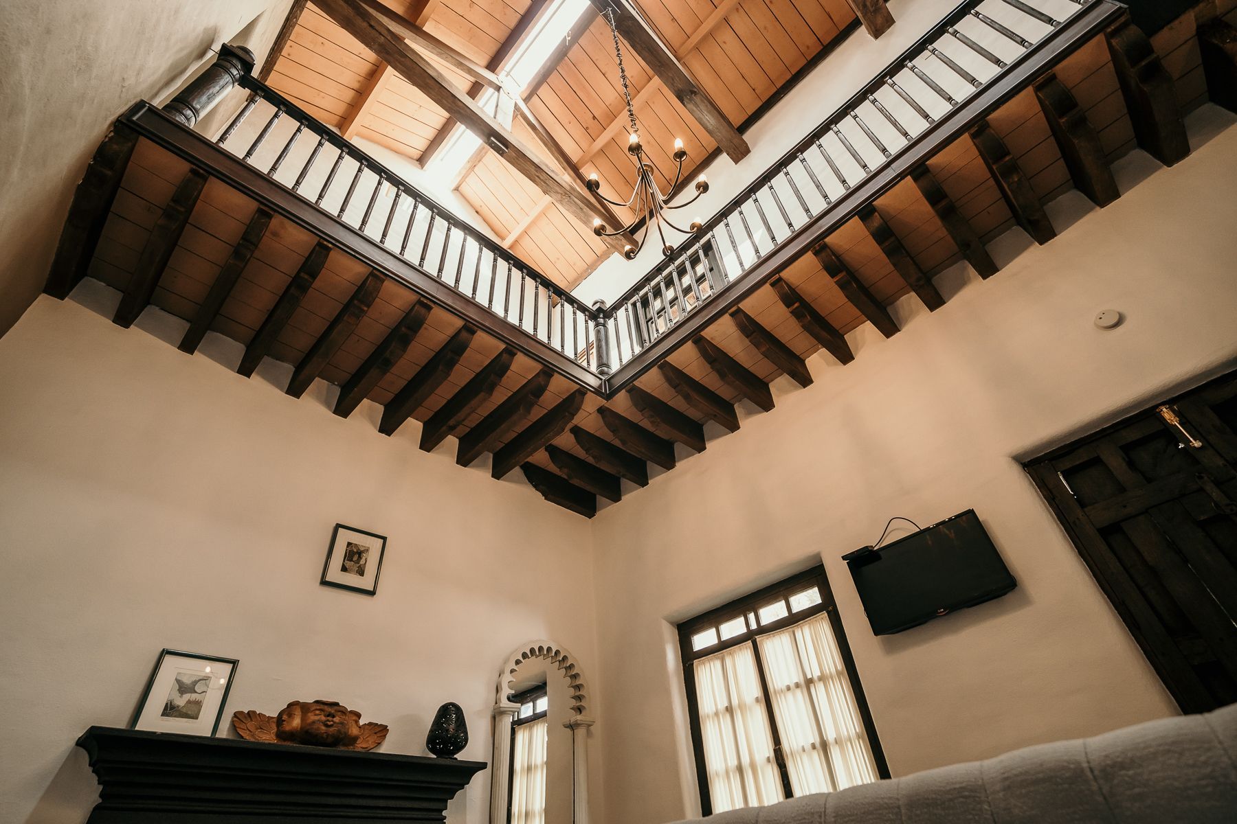 Interior de una habitación con techo alto, balcón y lámpara de araña.