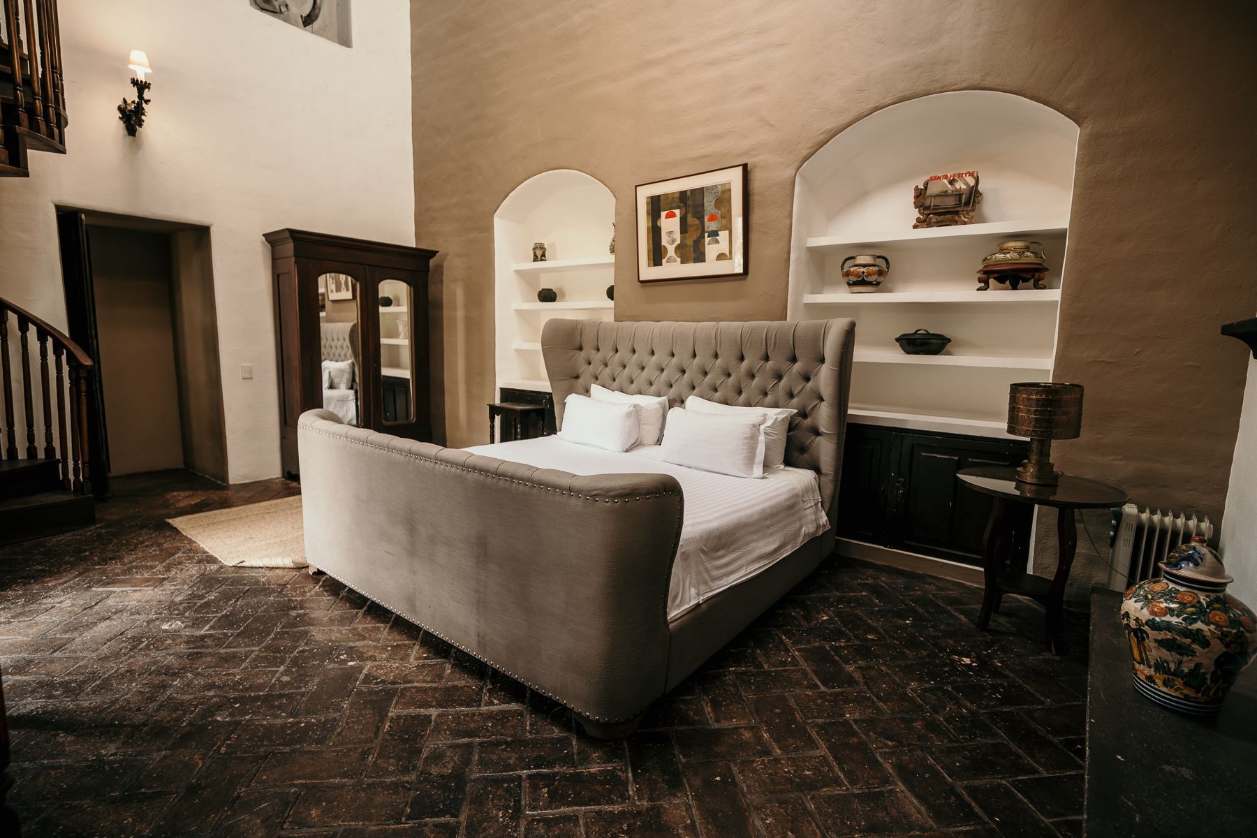 Dormitorio con cama grande, estantes empotrados, piso de madera oscura y techos altos.