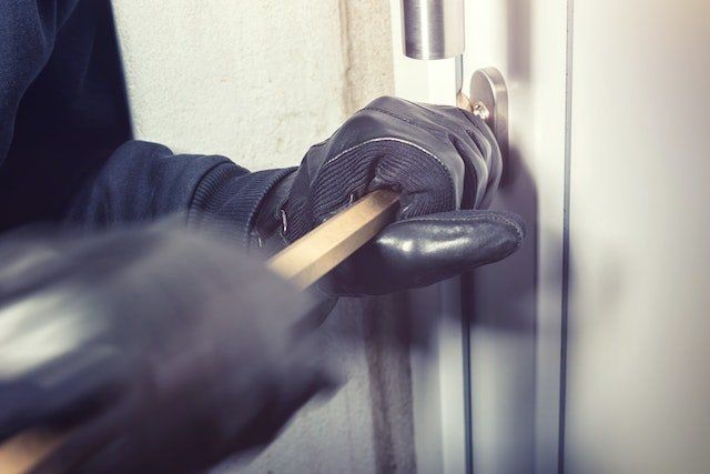 burglar in black gloves with crowbar