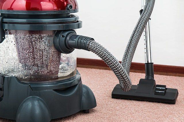 large black and red vacuum cleaner on light brown carpet