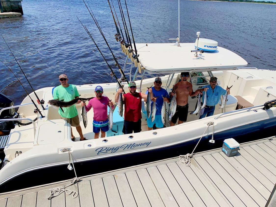 A group of men are standing on the deck of a boat holding fish.