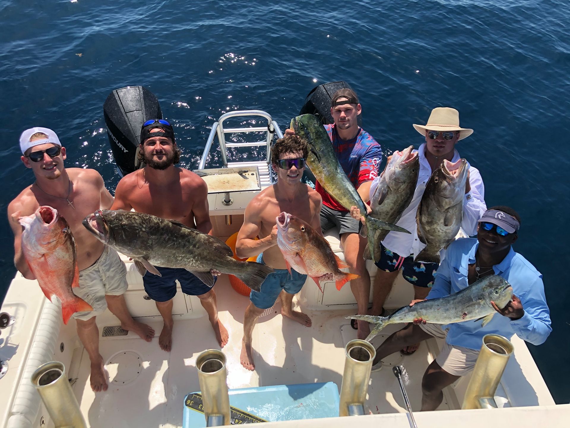 A group of men are standing on a boat holding fish.