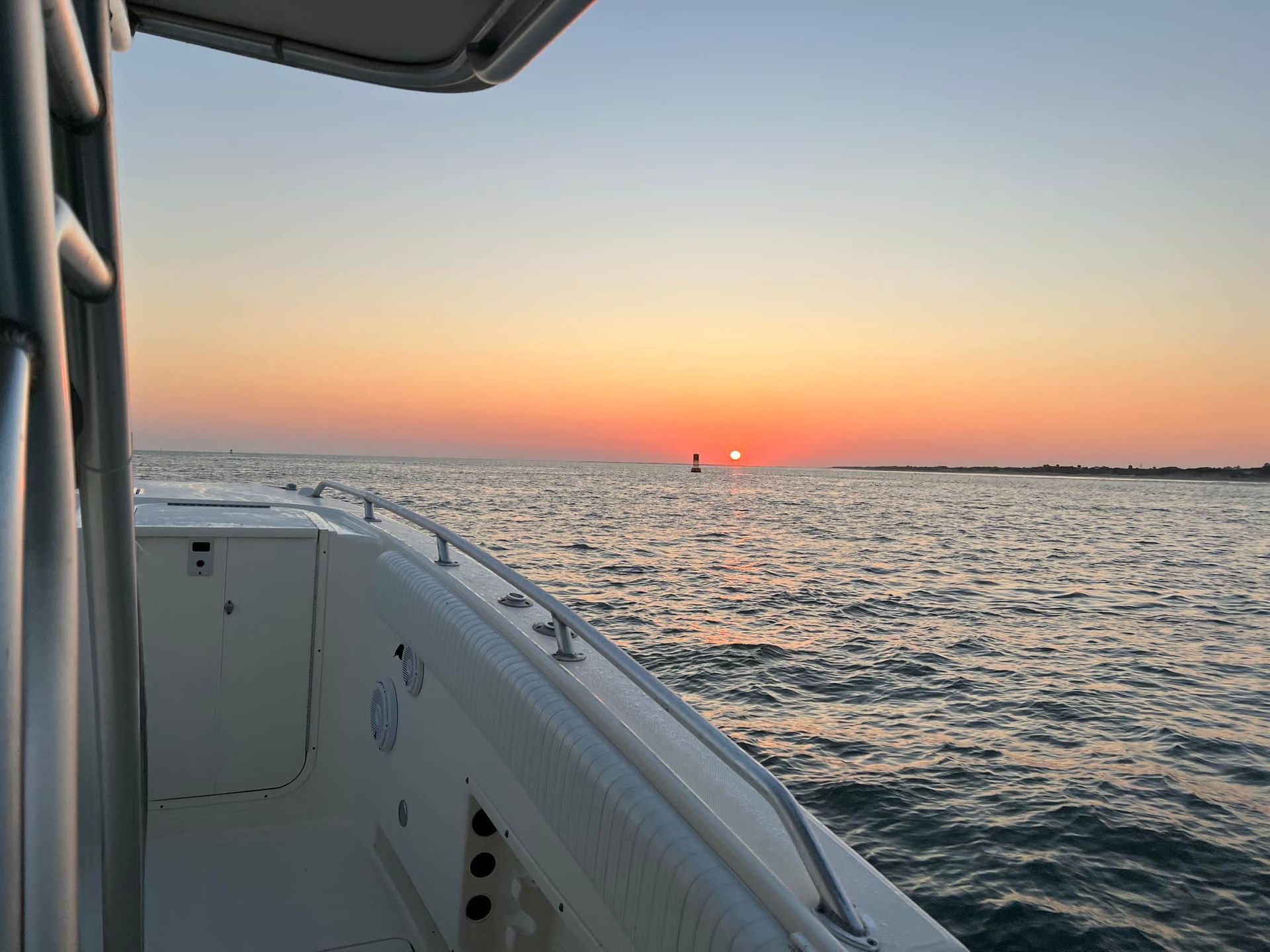 A boat is floating in the ocean at sunset