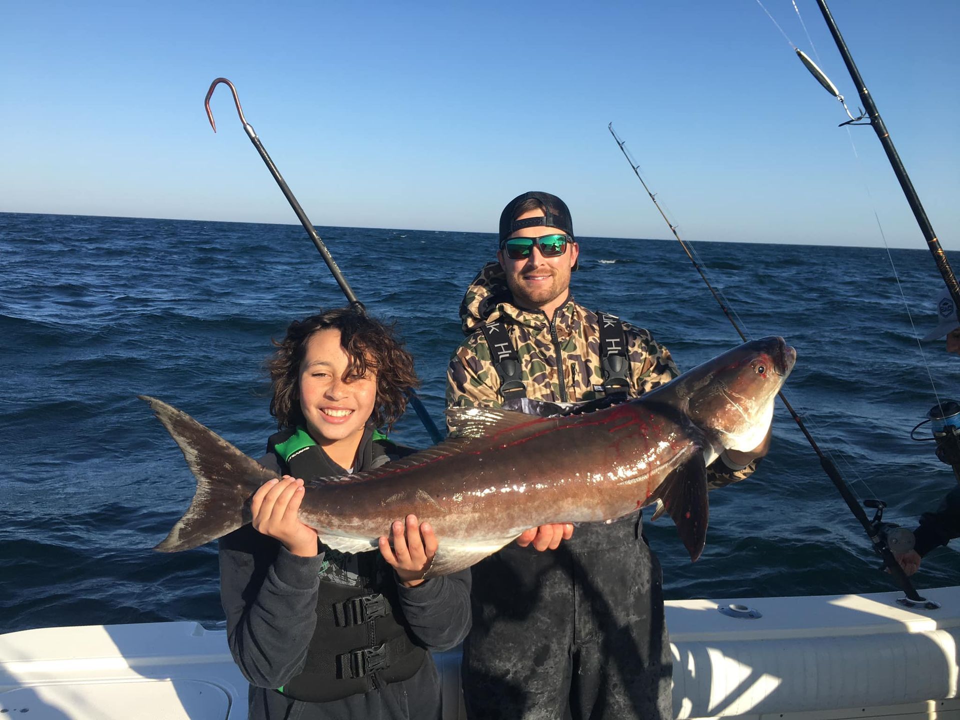 A man and a woman are holding a large fish on a boat.