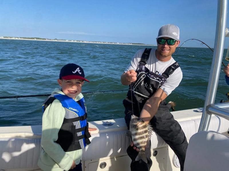 A man and a boy are fishing on a boat in the ocean.