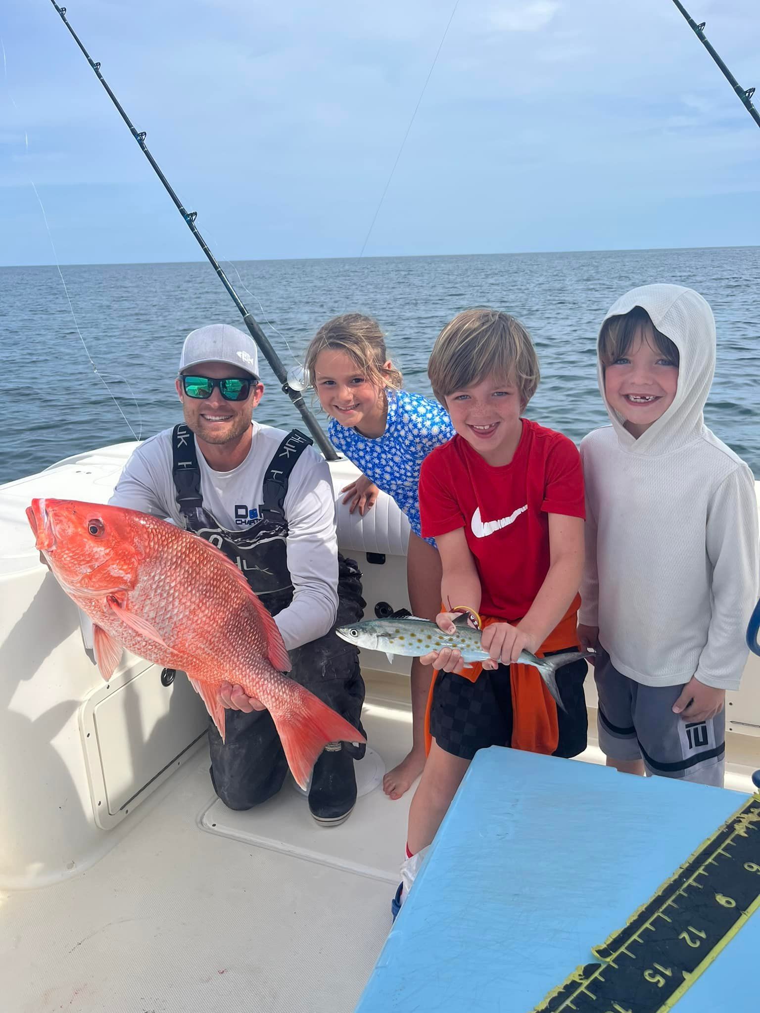 A man and three children are holding a large fish on a boat.