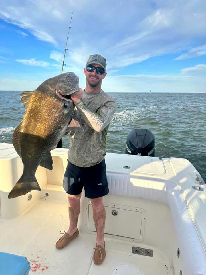 A man is standing on a boat holding a large fish.
