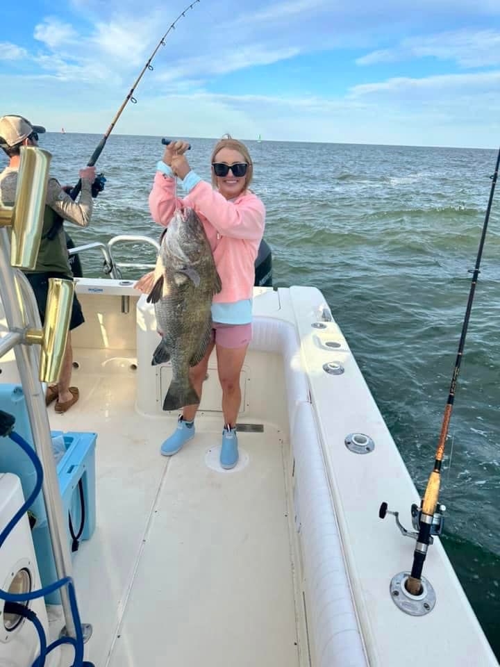 A woman is holding a large fish on a boat.