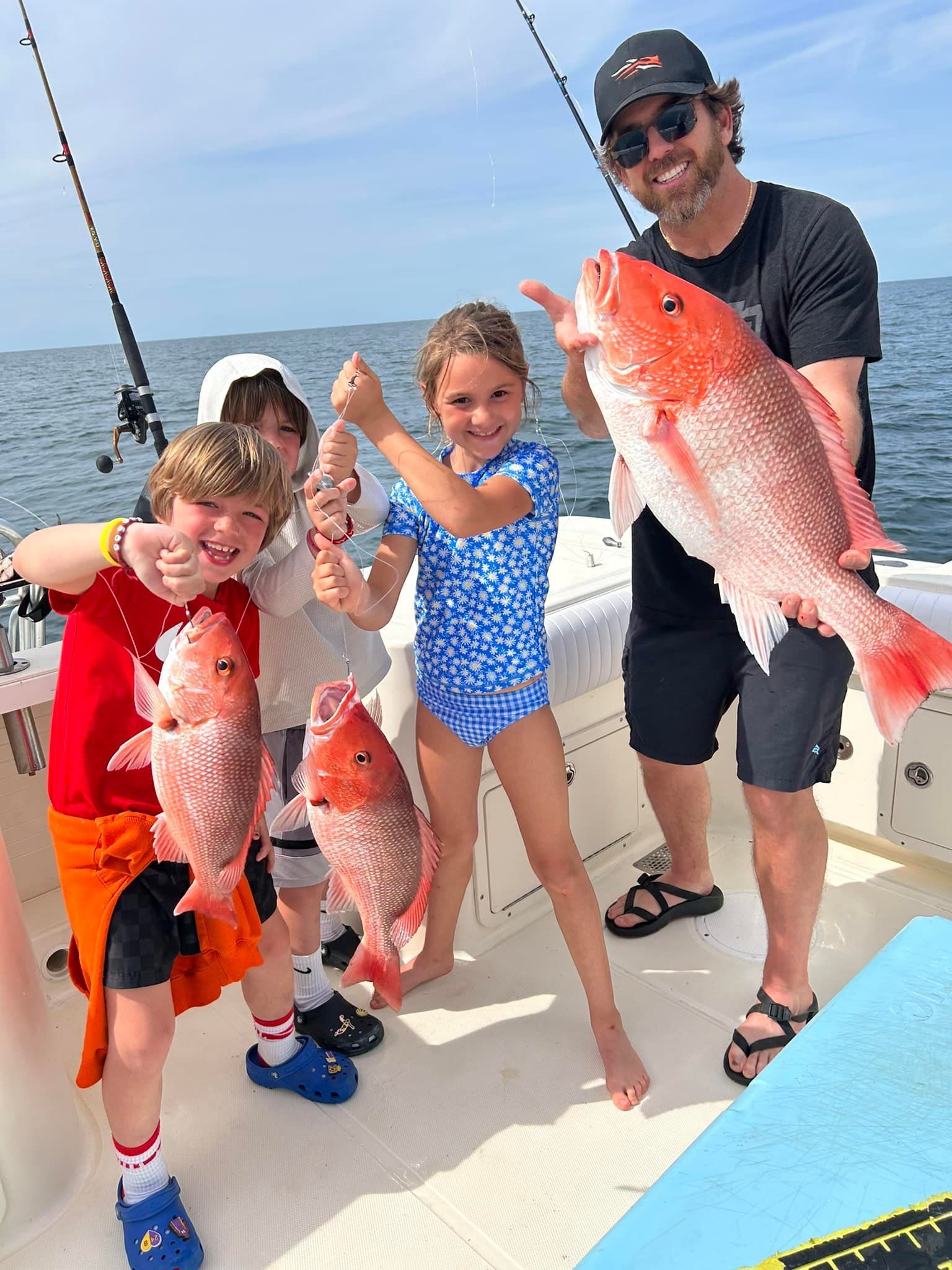 A man and three children are holding fish on a boat.