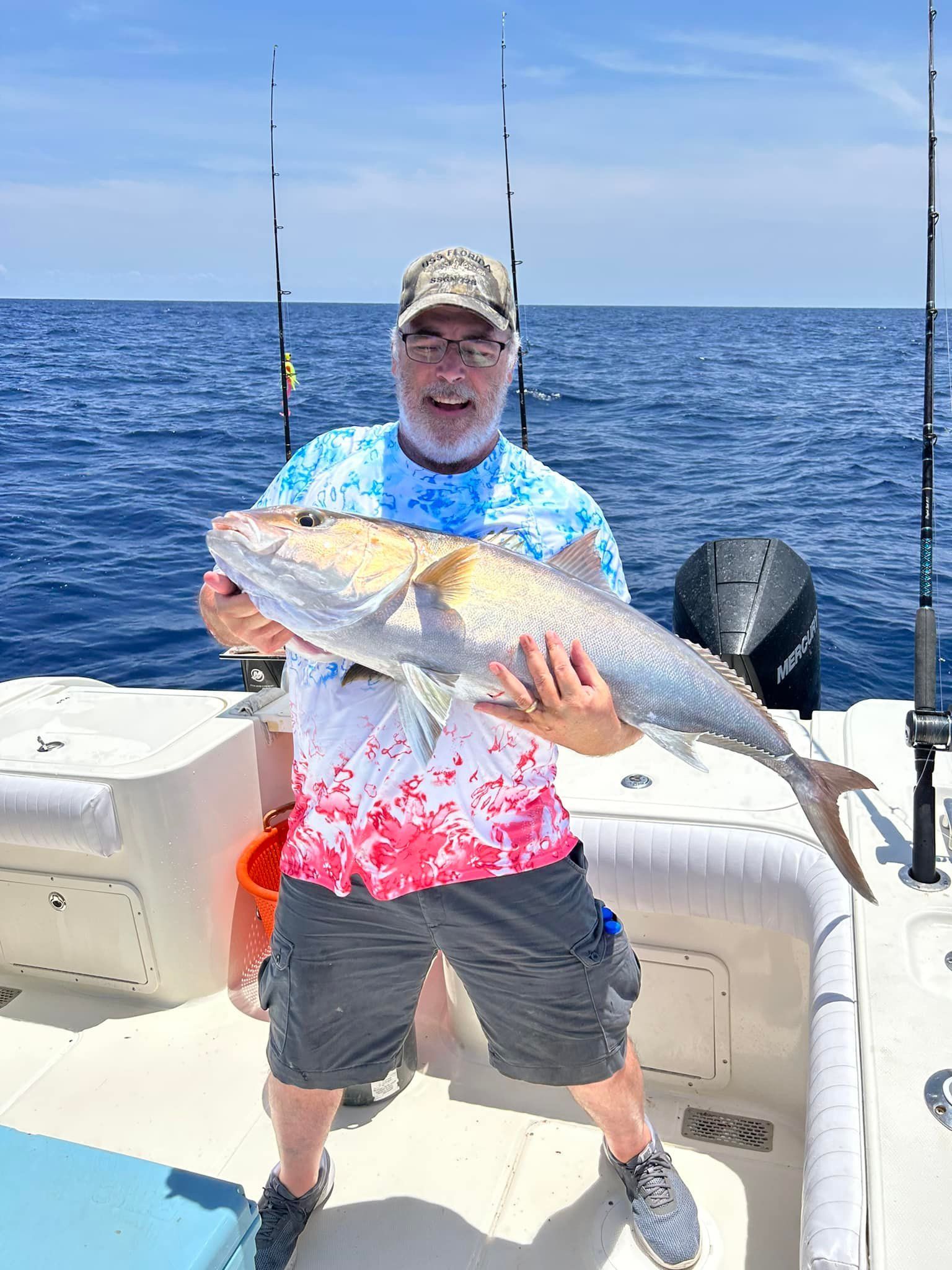 A man is holding a large fish on a boat in the ocean.