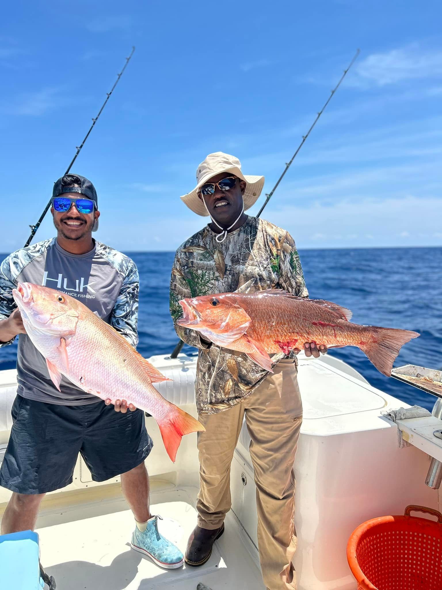 Two men are standing on a boat holding fish.