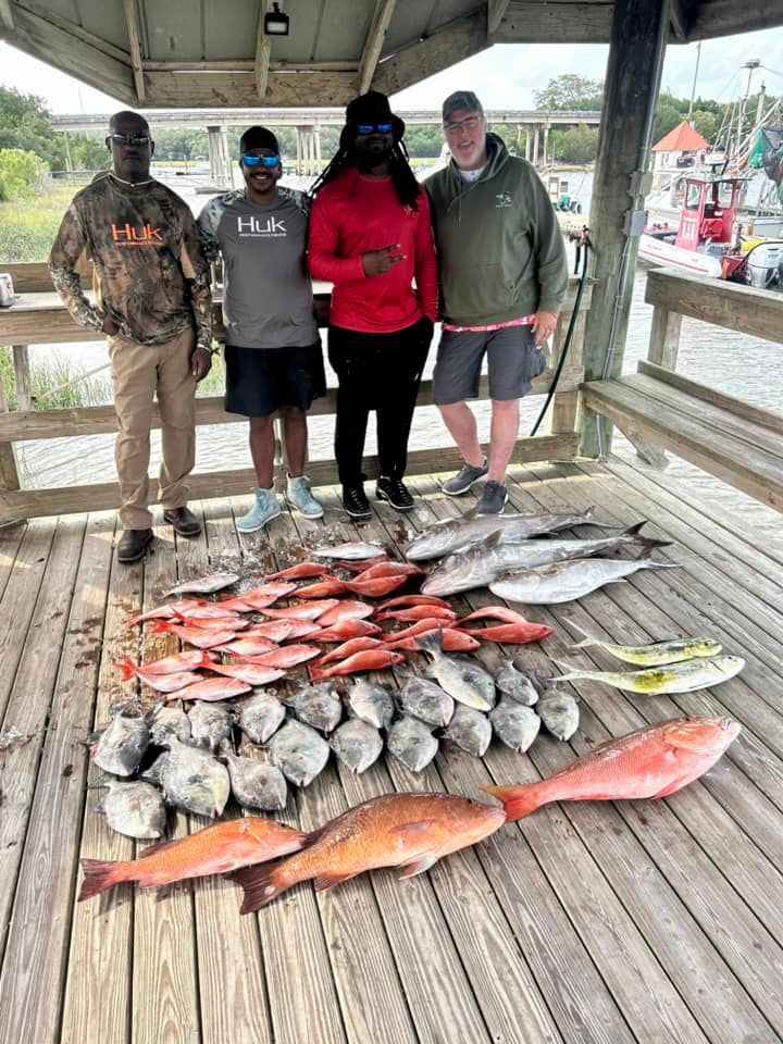 A group of people standing next to a pile of fish on a wooden deck.