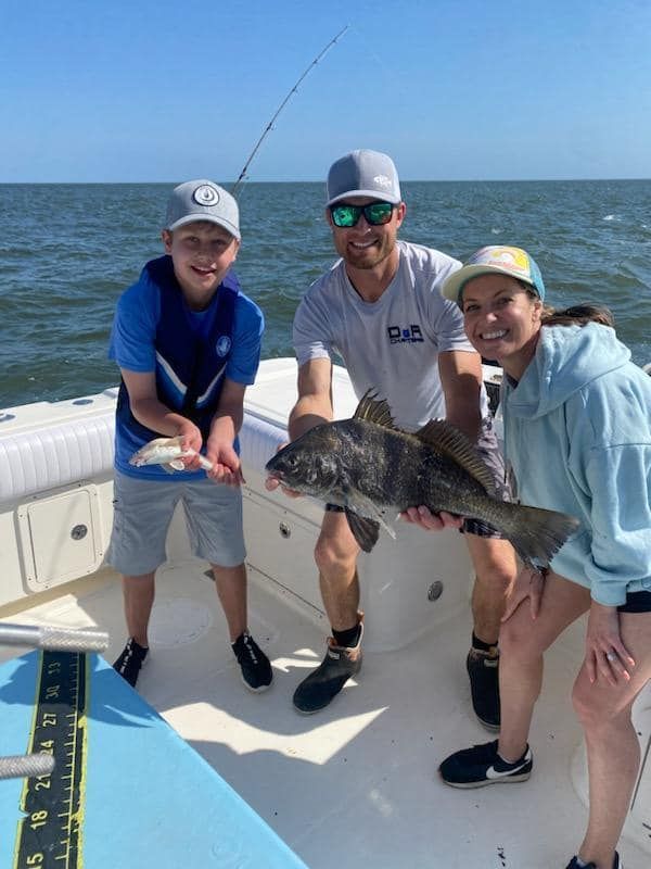 A man and two children are holding a large fish on a boat.
