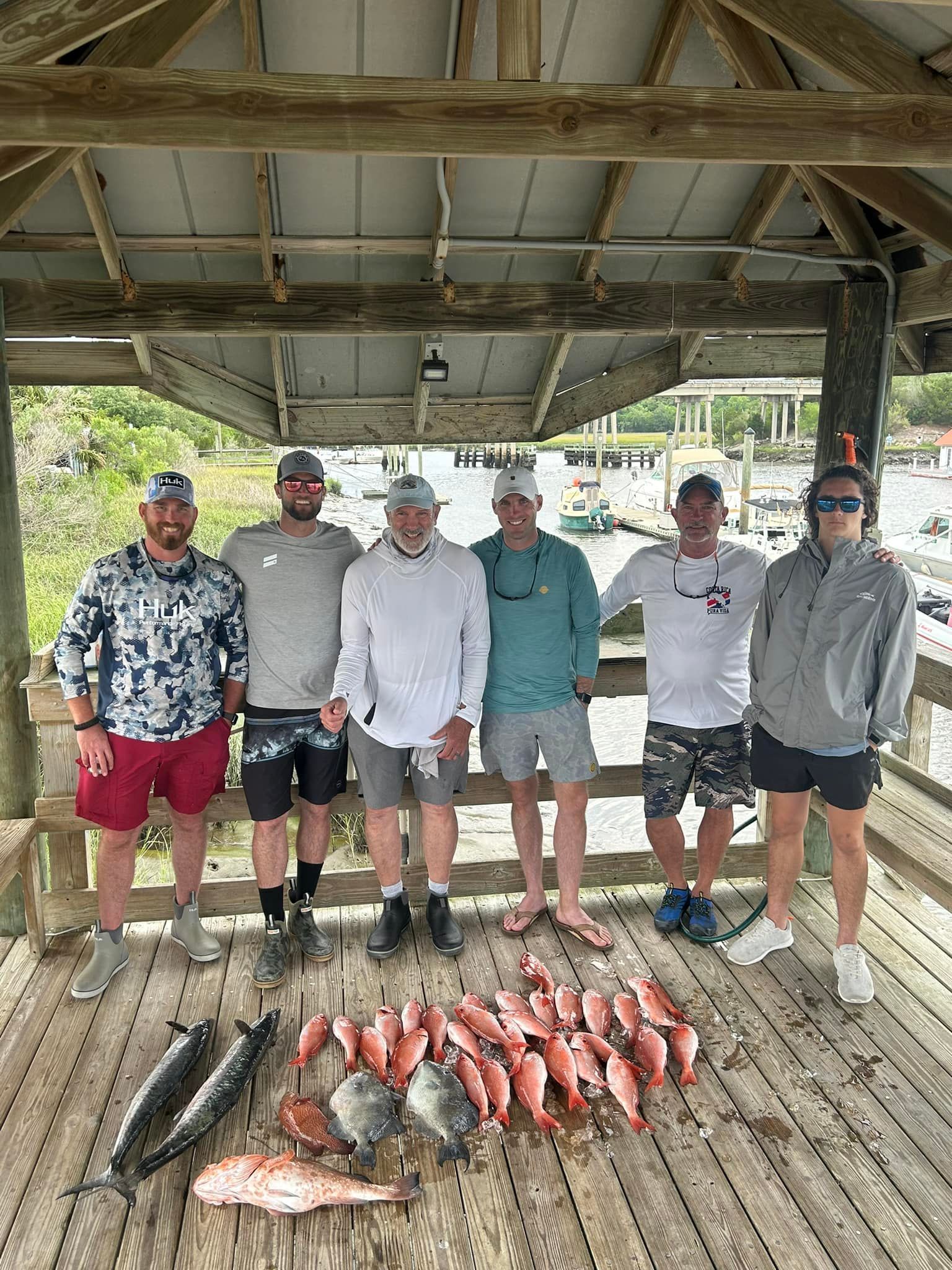 A group of men are posing for a picture with their catch of fish.