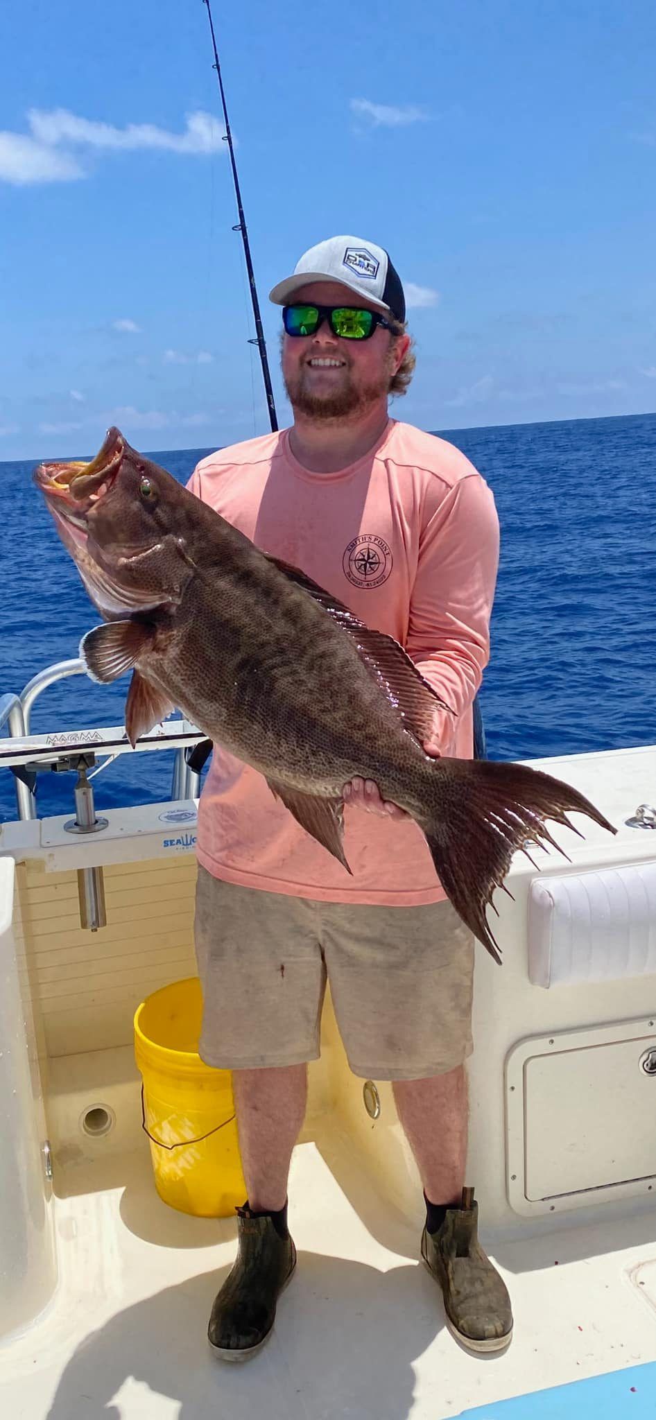 A man is standing on a boat holding a large fish.