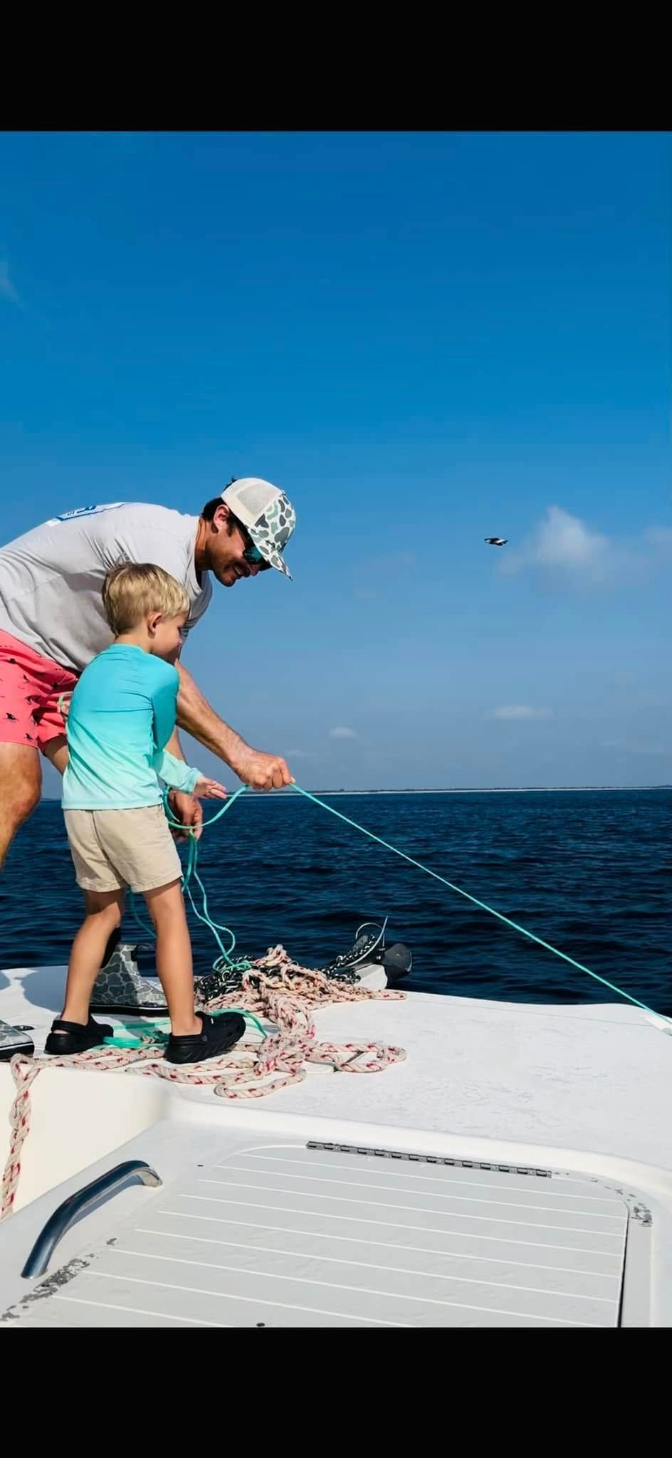 A man and a boy are fishing on a boat in the ocean.