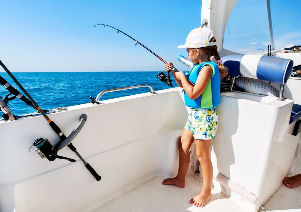 A little girl is fishing on a boat in the ocean.