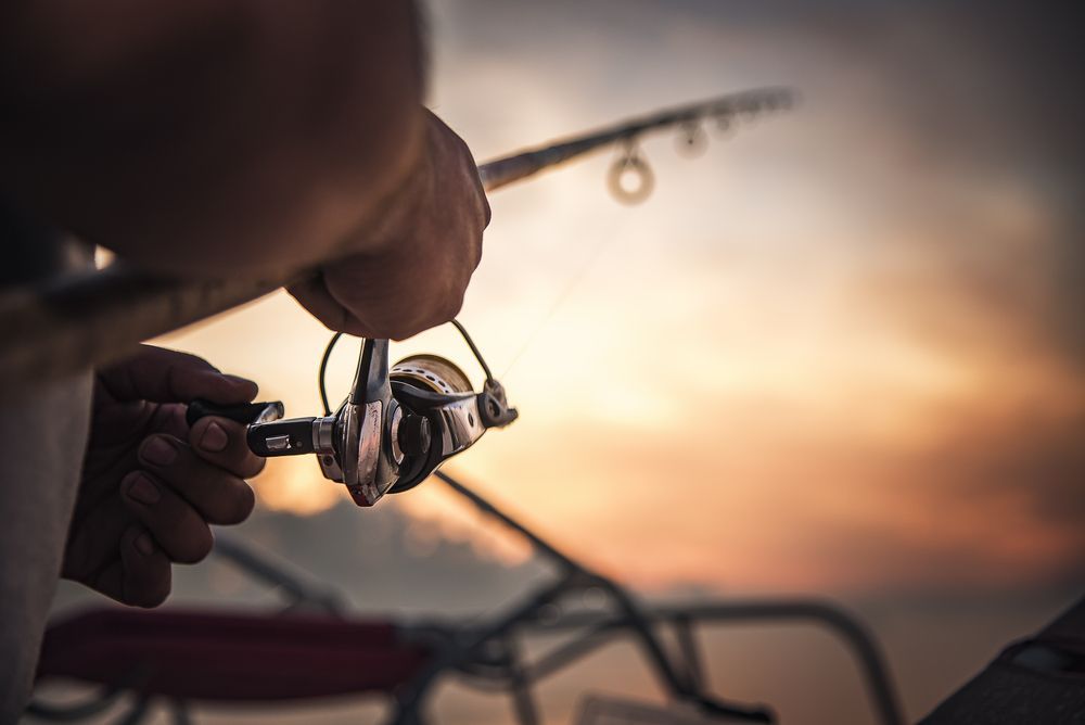 A person is holding a fishing rod and reel in their hands.