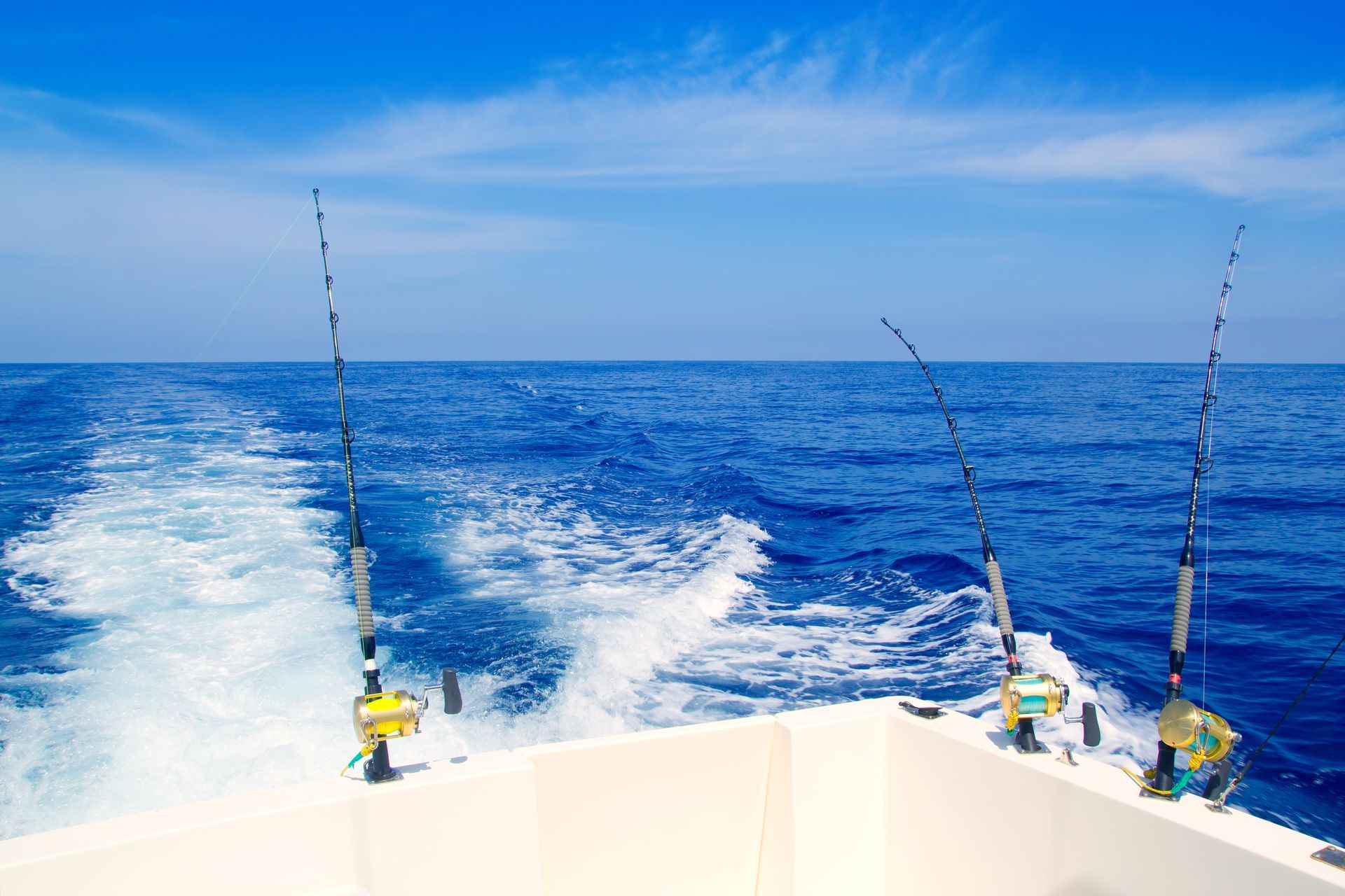 A boat with fishing rods on it is floating on top of a large body of water.