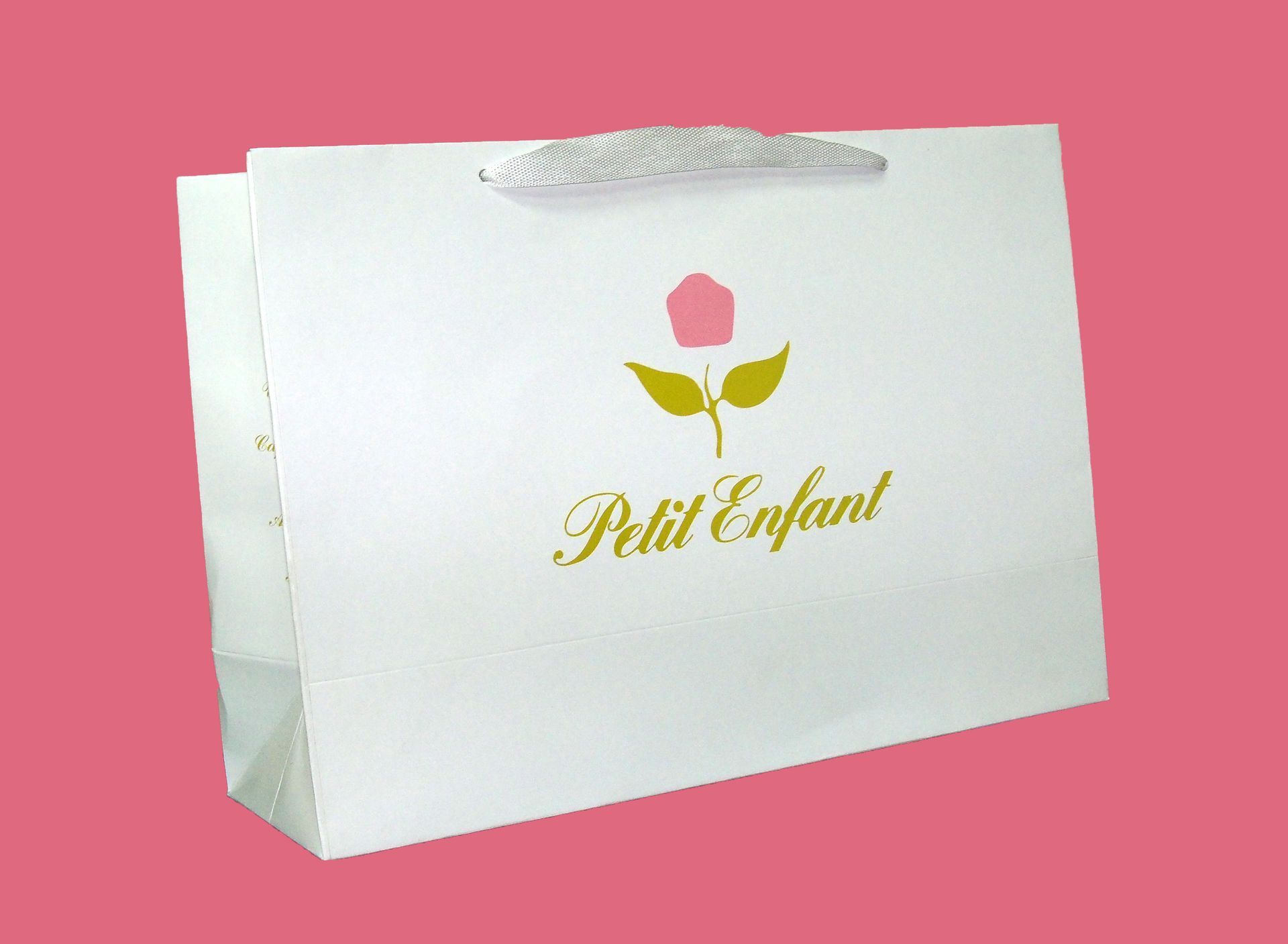 Una bolsa de regalo blanca con un icono de una rosa rosa y el texto dorado 