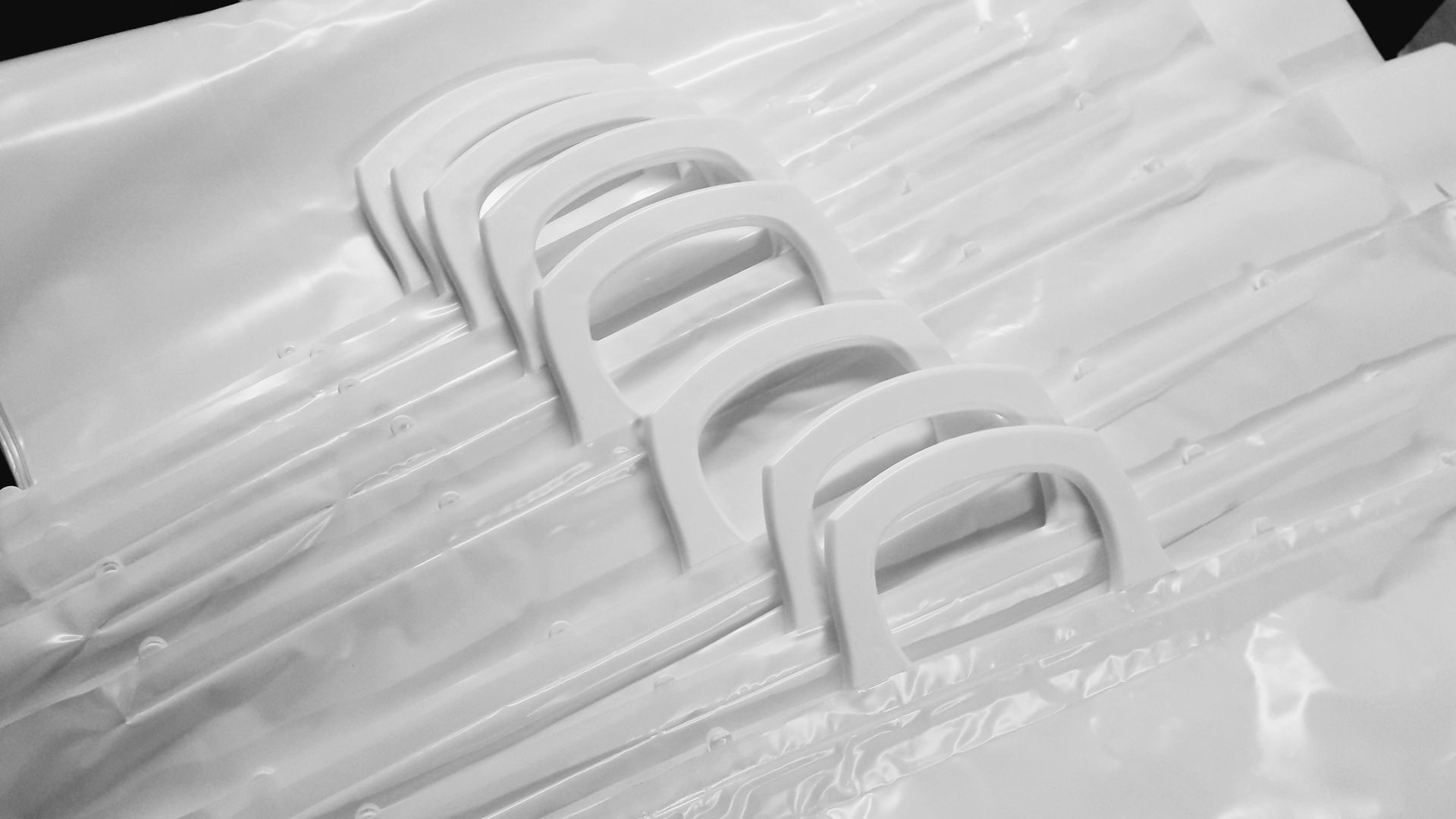 Una hilera de palillos de hilo dental de plástico blanco apilados sobre un fondo claro.