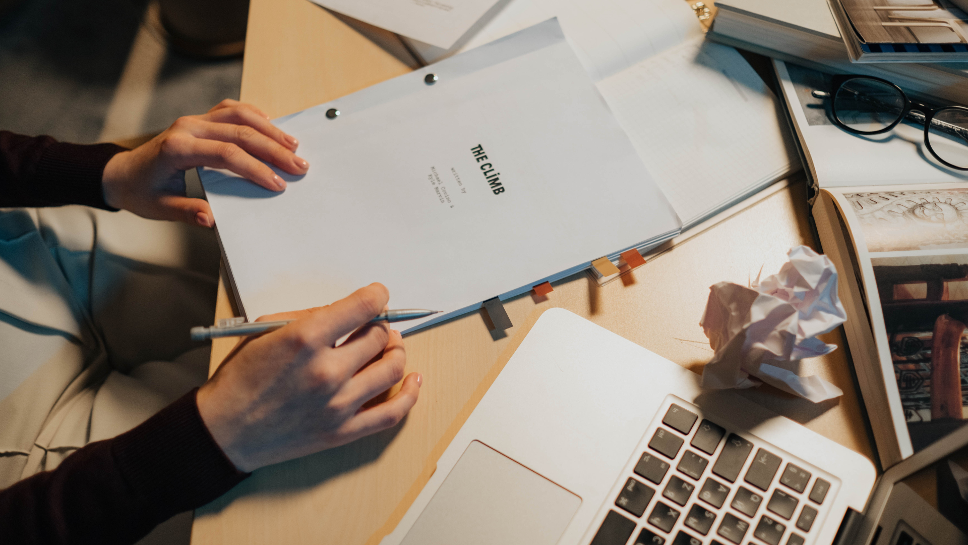 A person is sitting at a table writing on a script.