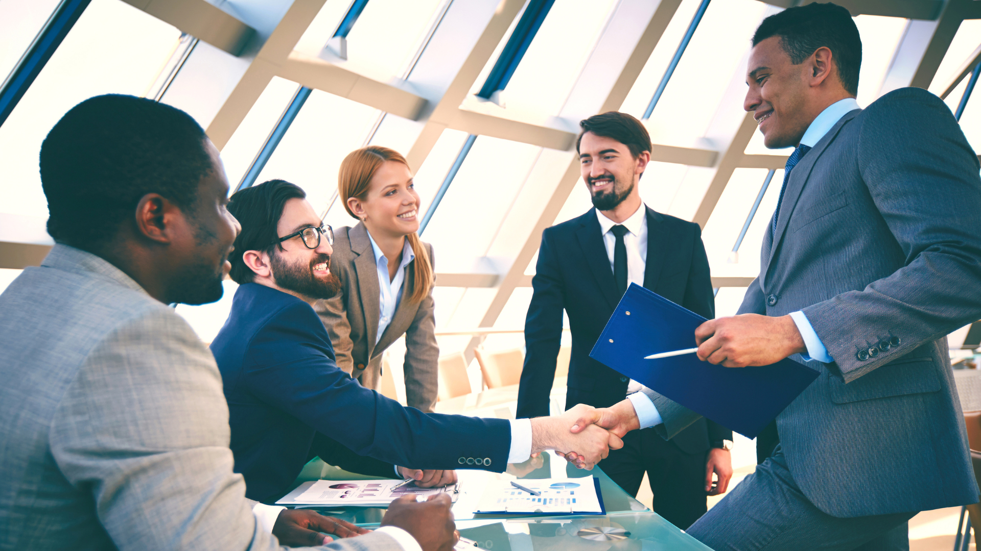 A group of business people are shaking hands in an office.