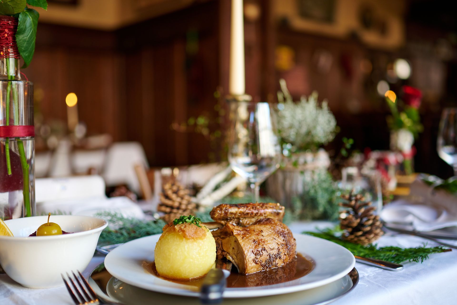 Festlich gedeckter Tisch mit einem Teller Essen, einem Teigtaschen und Blumenschmuck.