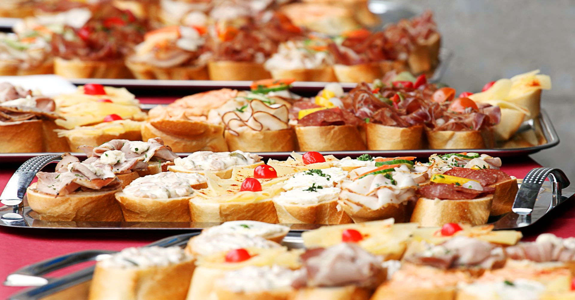 Platten mit verschiedenen Tapas auf geröstetem Brot, darunter Fleisch, Käse und Gemüse.