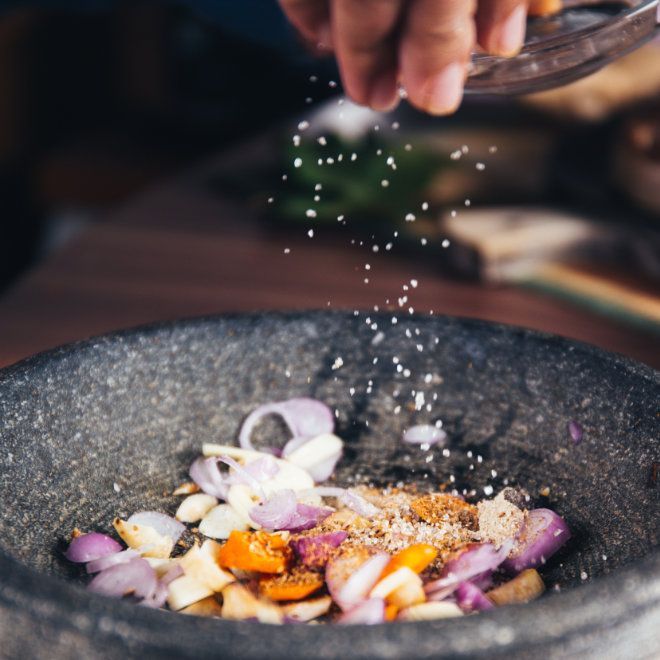 Die gehackten Zutaten werden von Hand in einem Mörser mit Salz gewürzt.