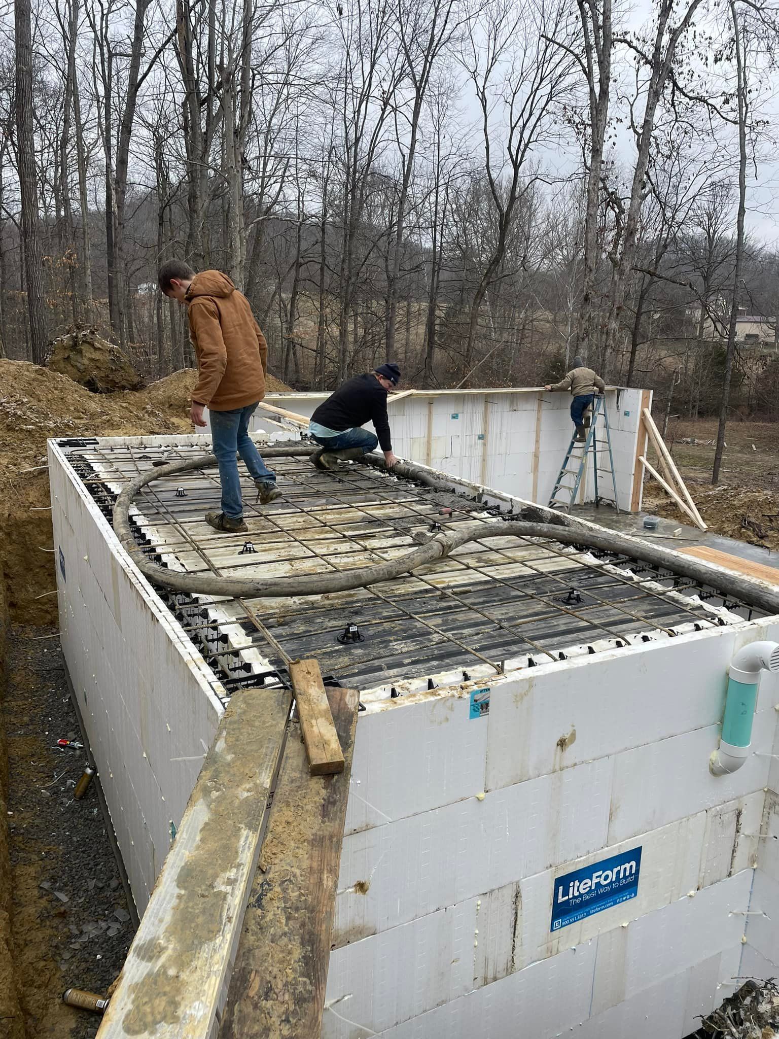 A couple of men are working on a large concrete wall.