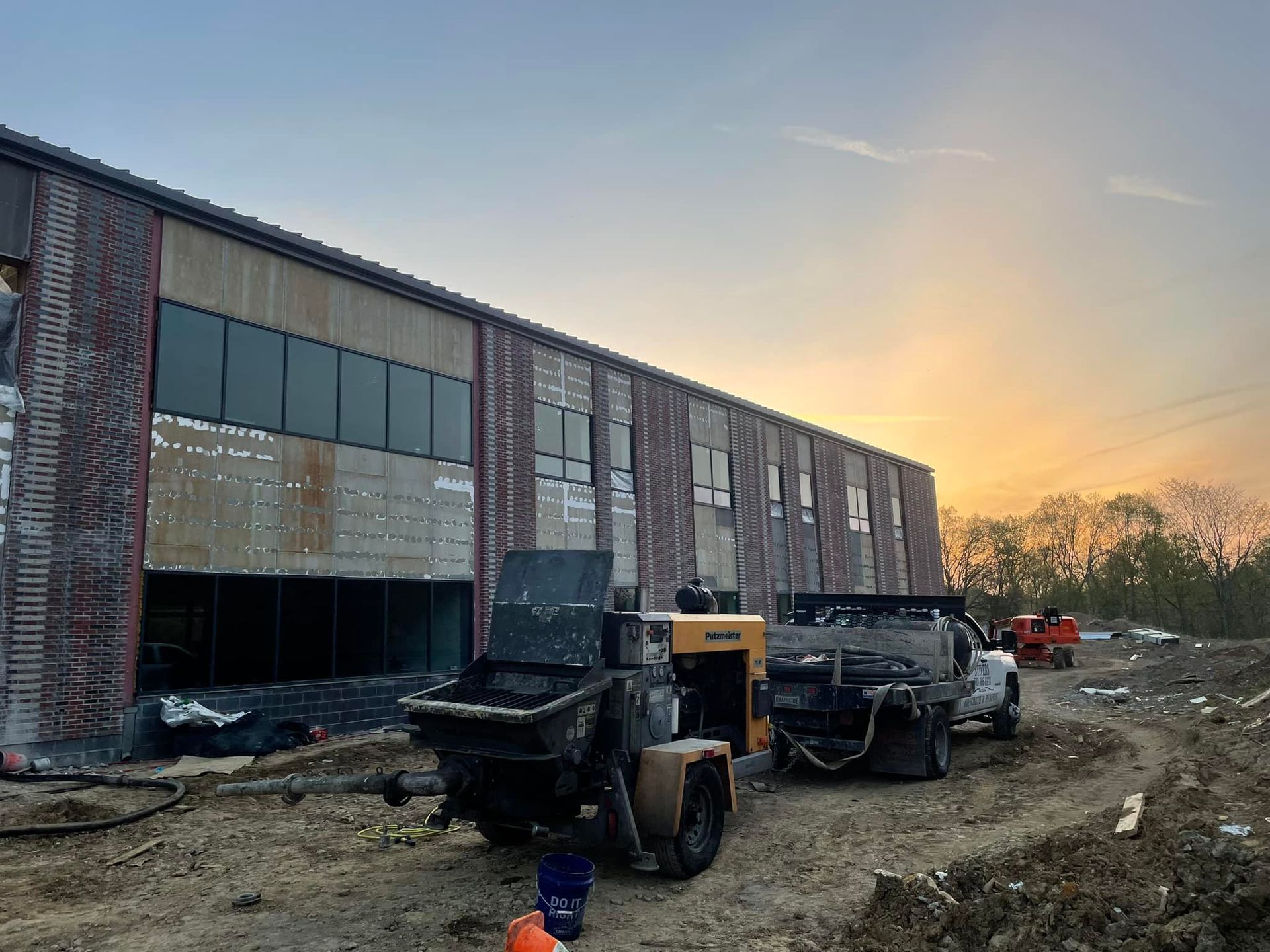 A building under construction with a lot of machinery parked in front of it.