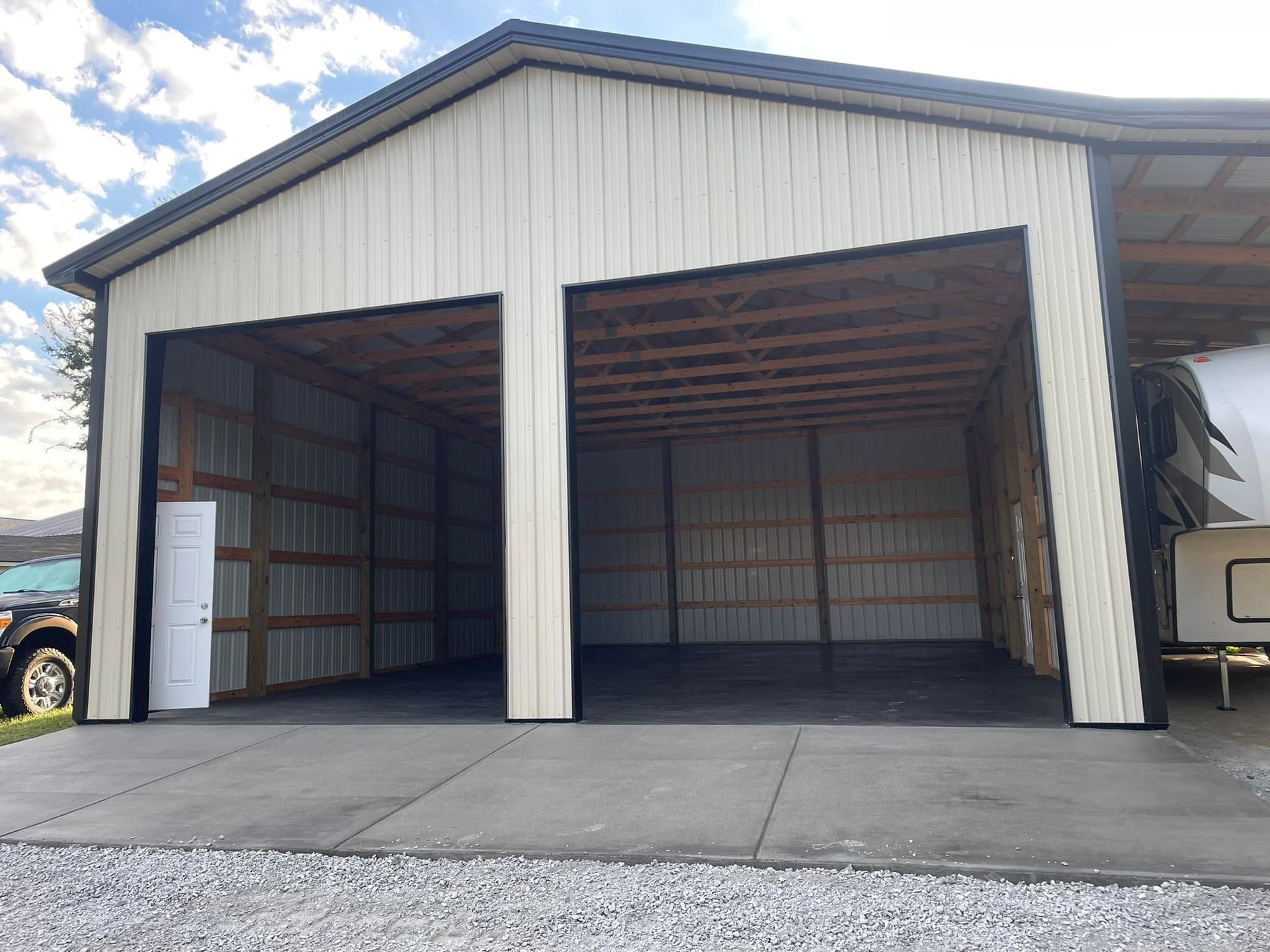 A garage with two doors open and a trailer parked inside of it.