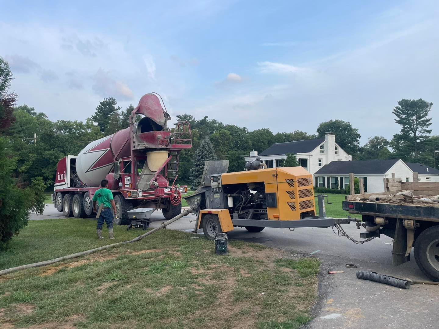 A concrete mixer truck is being towed by a trailer.