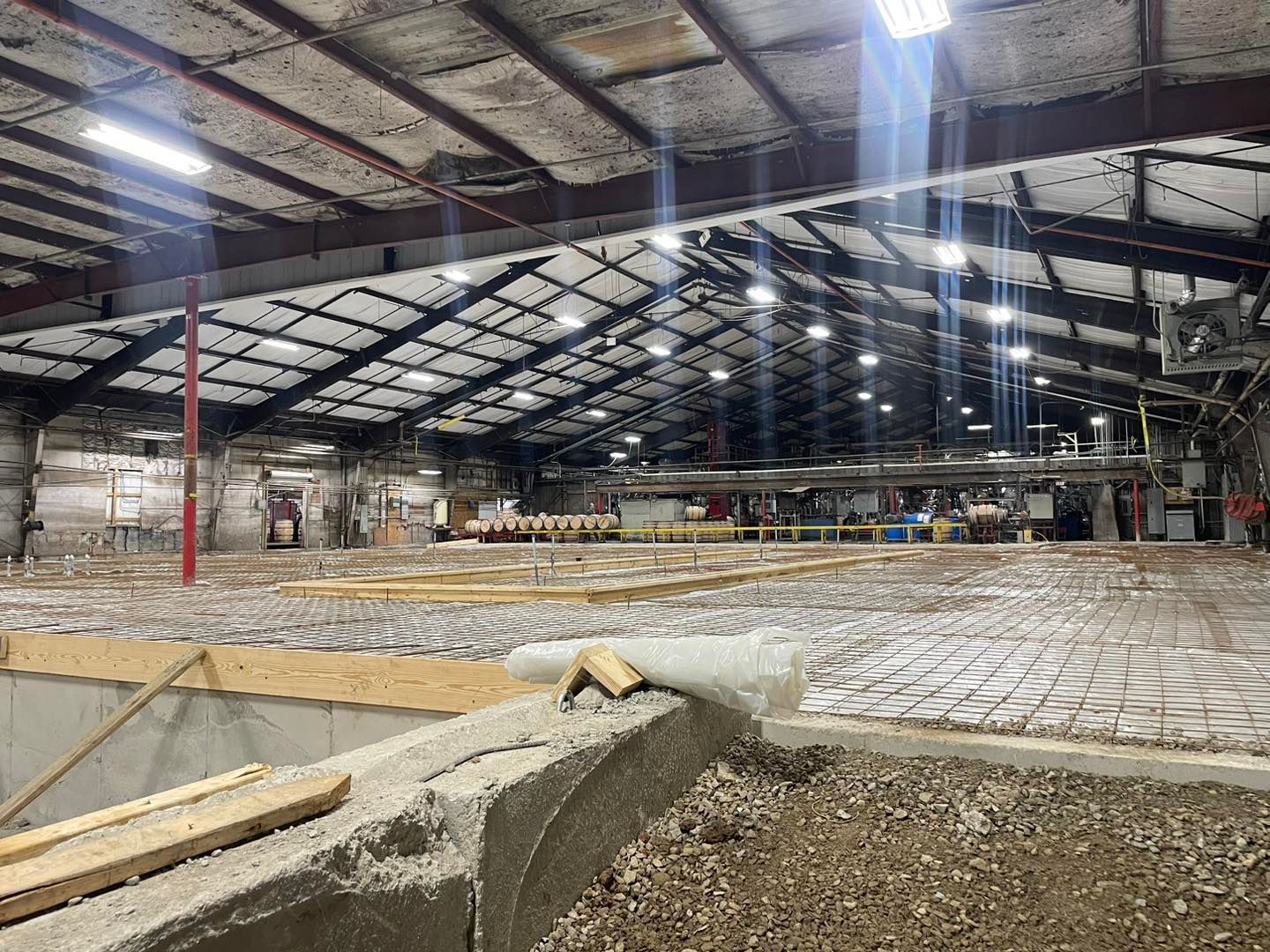 The inside of a large building under construction with a lot of lights on the ceiling.