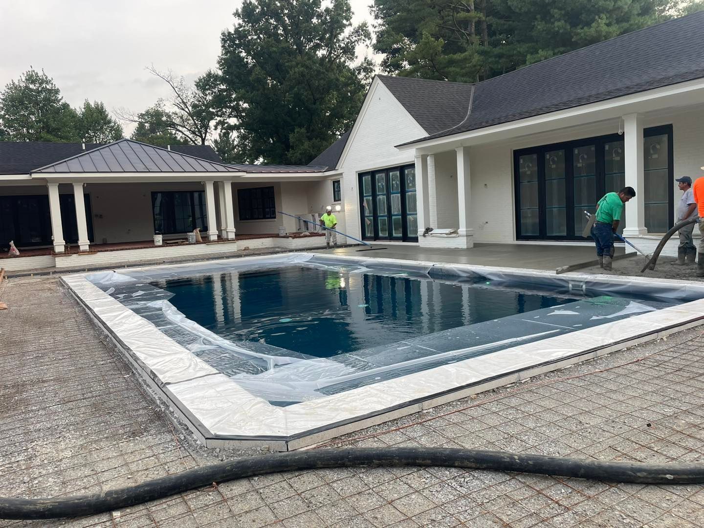 A large swimming pool is being built in front of a house.