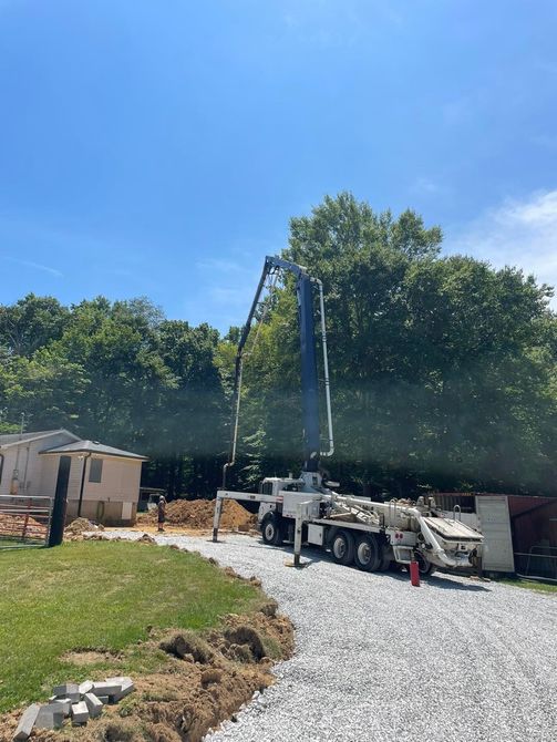 A concrete pump is being used to pump concrete into a gravel driveway.