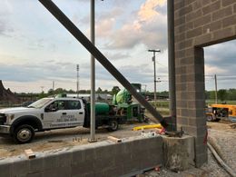 A truck is parked next to a concrete mixer on a construction site.