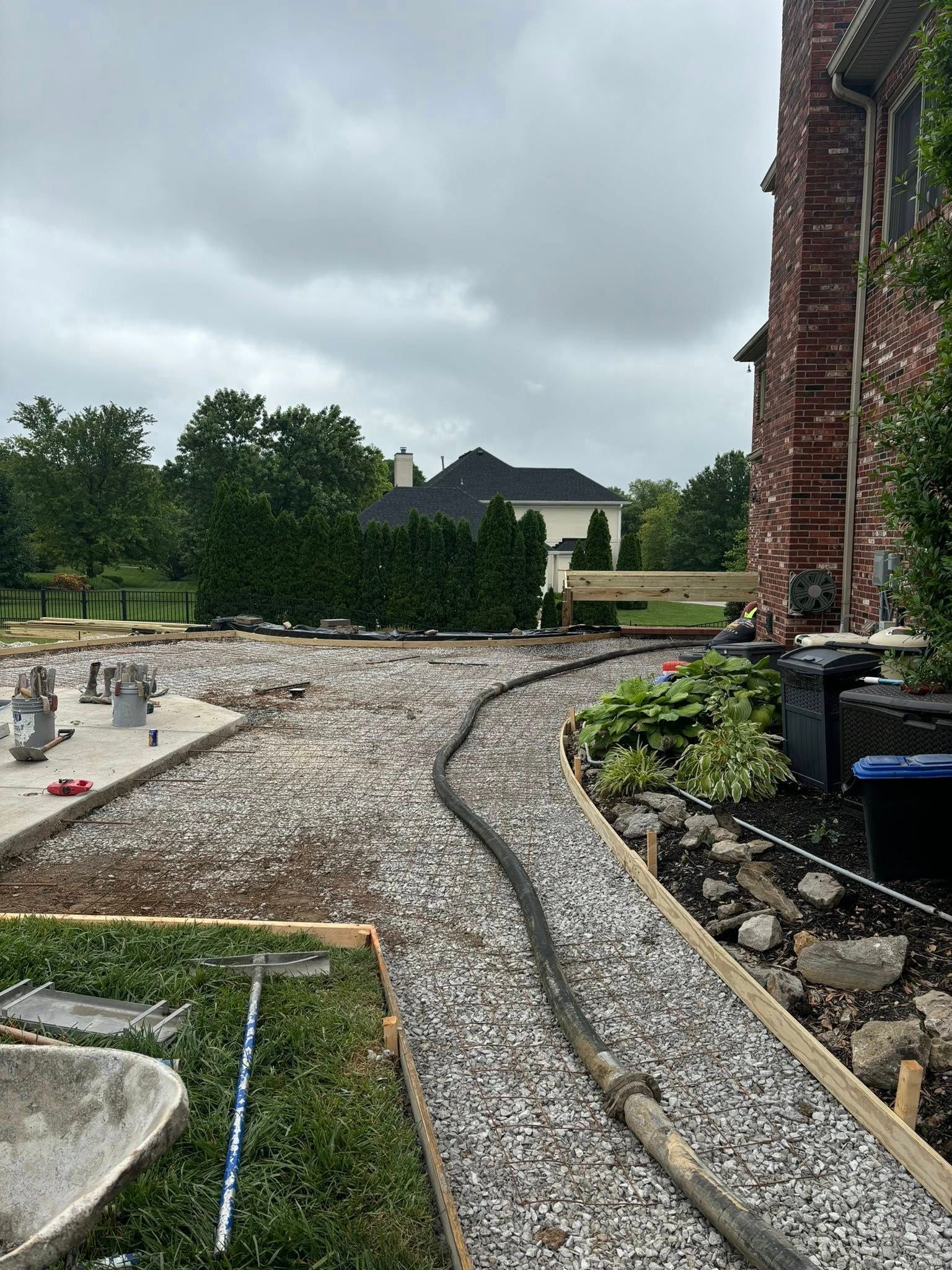 A gravel driveway is being built in front of a brick house.