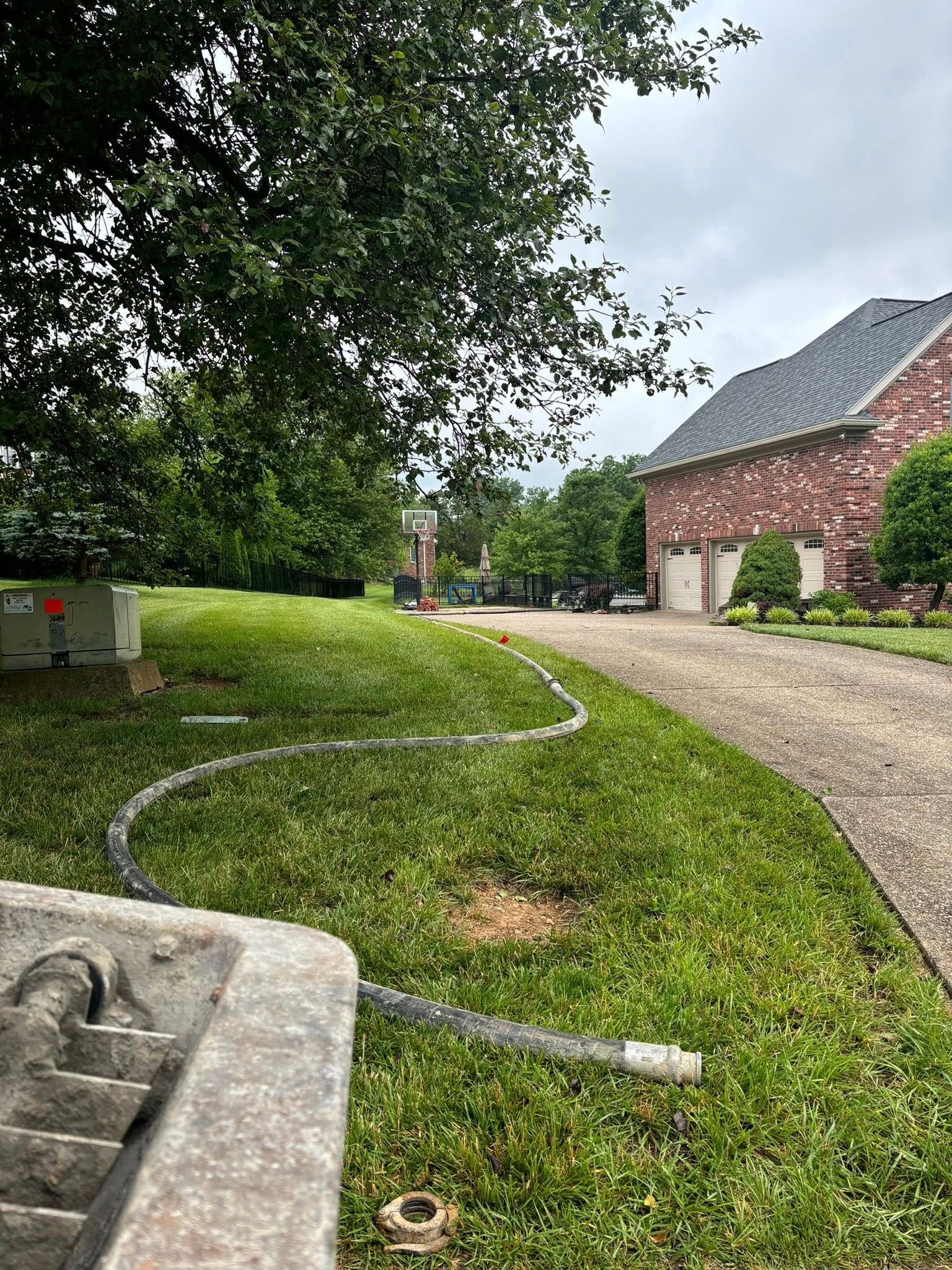 A hose is laying in the grass in front of a house.